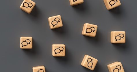 many cubes with speech bubble icons and smartphone on wooden bac