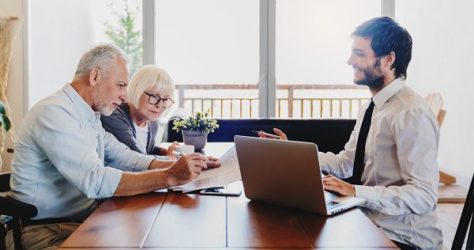 Senior couple planning their investments with financial advisor in living room at home